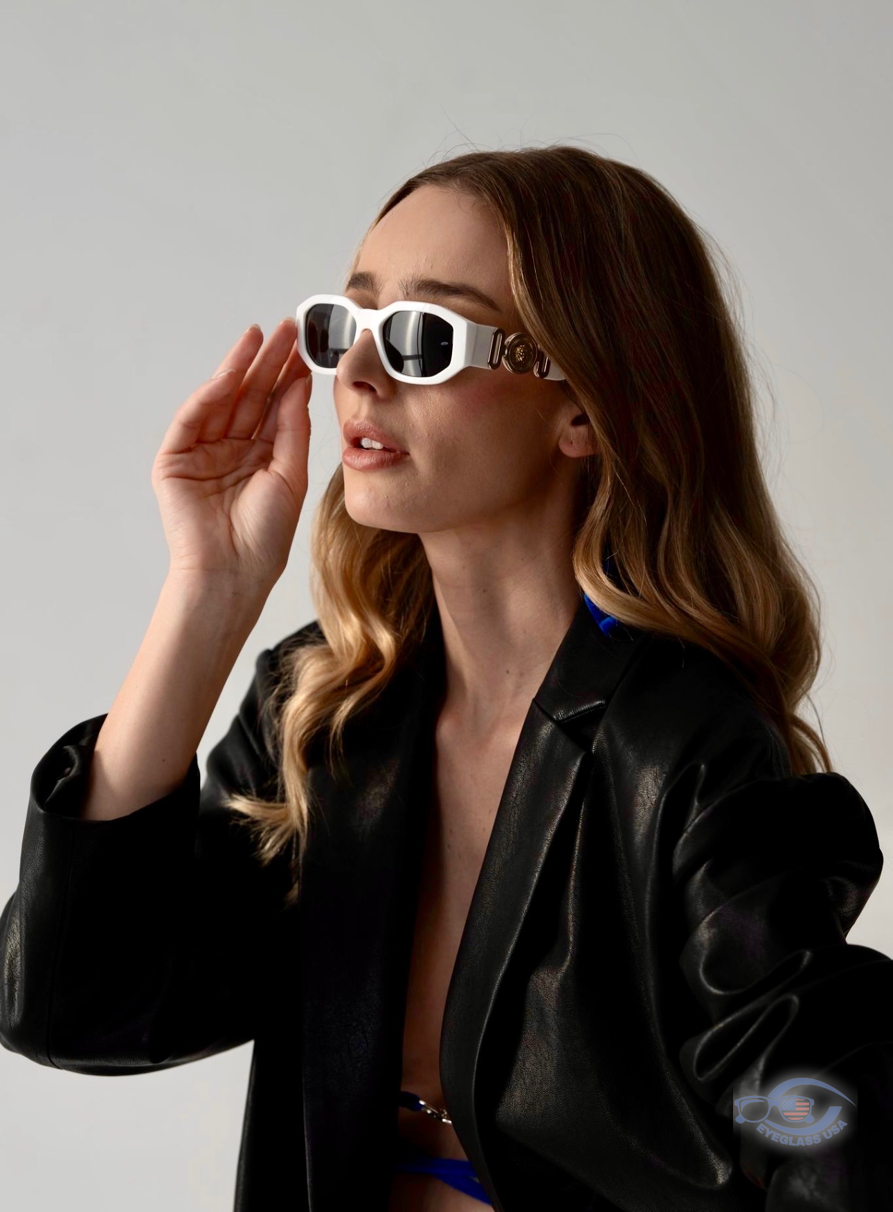 Customer adjusting white Versace sunglasses with leather jacket